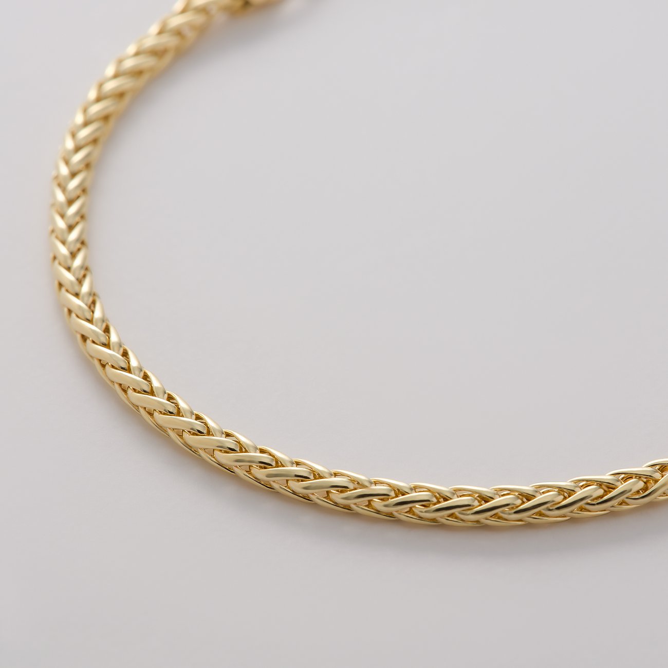 Nahaufnahme eines CHRIST 375er Gelbgold Armschmucks, der ein detailliert geflochtenes Muster zeigt.