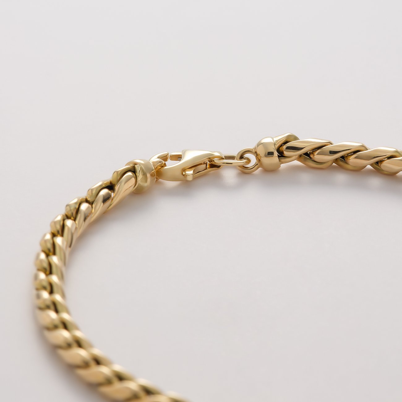 Nahaufnahme des CHRIST Gelbgold 585er Armschmucks mit Karabinerverschluss auf weißem Hintergrund.