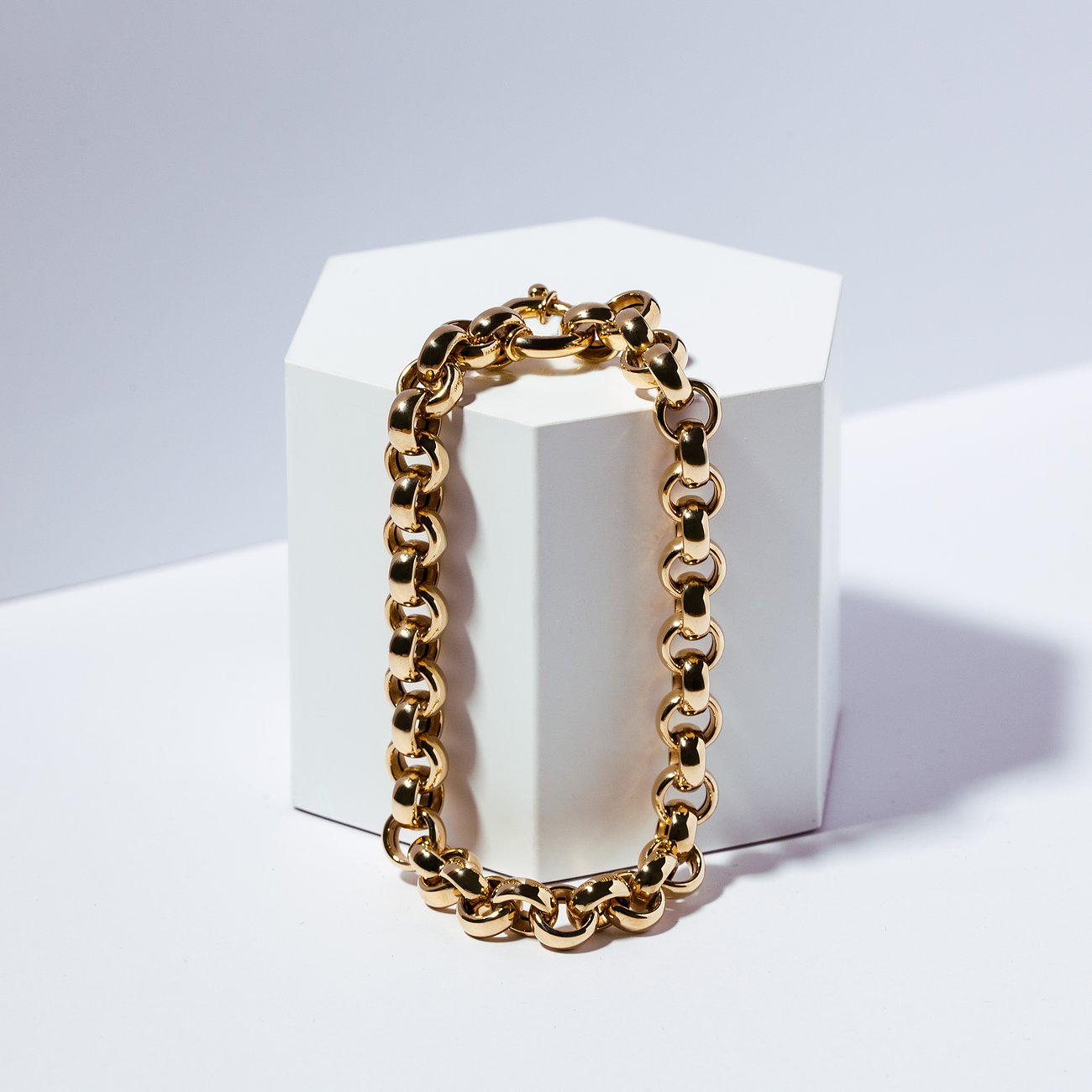 CHRIST armband van gepolijst 585 geelgoud, liggend rond een witte kubus, toont de grove schakelketting.