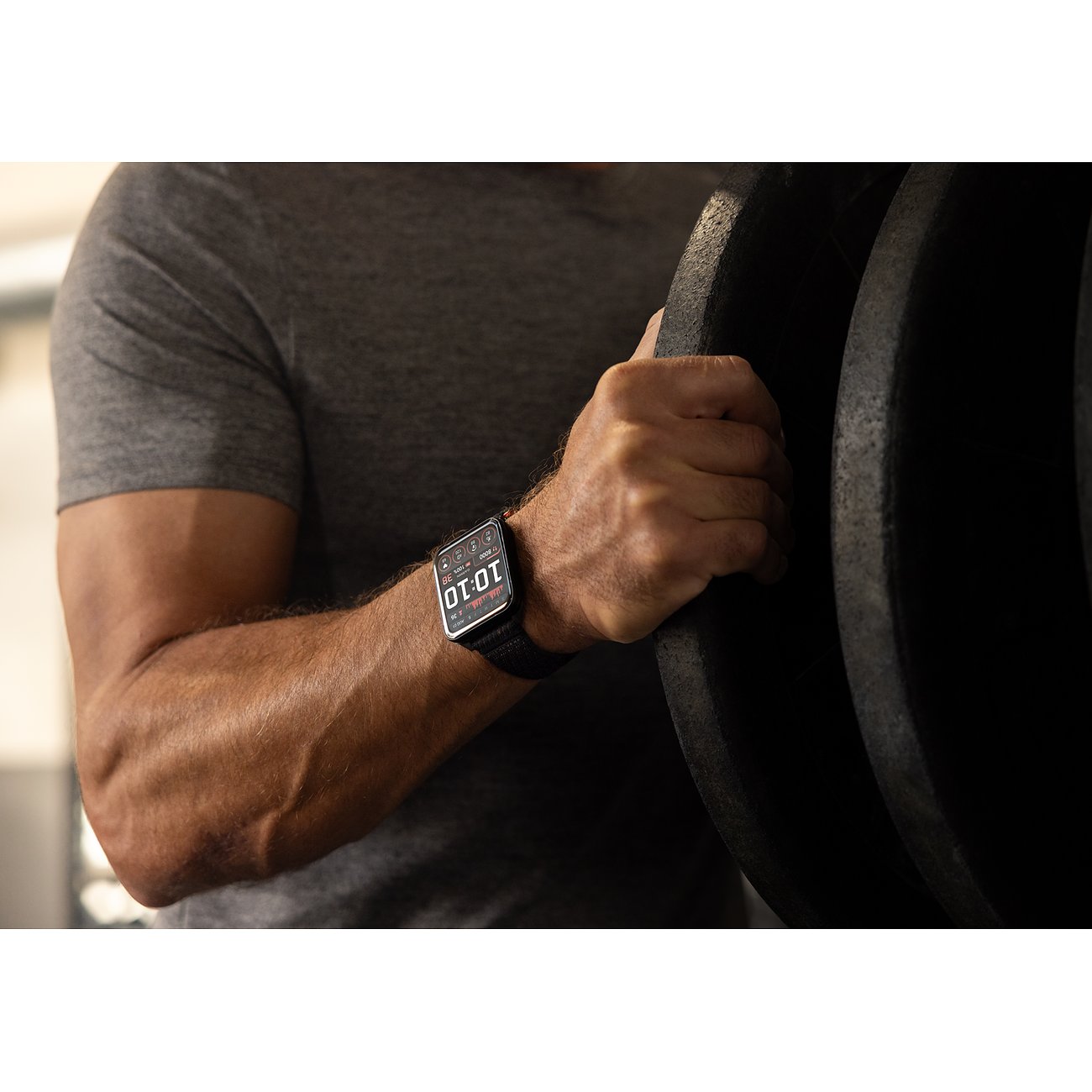 Ein Mann mit der Garmin Smartwatch aus Kunststoff und Metall am Handgelenk, während er Gewichte stemmt.