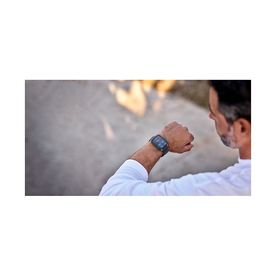 Eine Person trägt die Garmin Smartwatch aus Kunststoff und Metall am Handgelenk und blickt darauf.