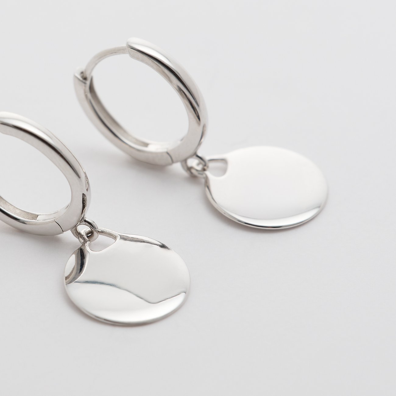FAVS örhängen i 925 silver med runda, glänsande plattor som hänger från cirkulära kreoler.