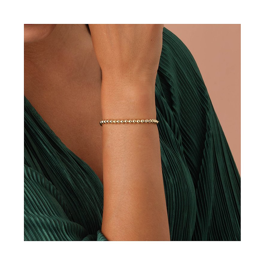Een goudkleurige CHRIST kralenarmband van 585 geelgoud is zichtbaar om iemands arm.