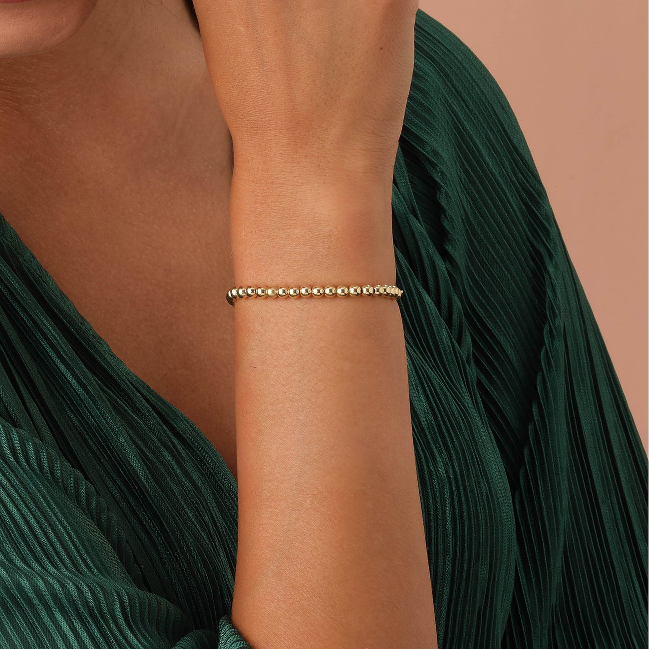 Een goudkleurige CHRIST kralenarmband van 585 geelgoud is zichtbaar om iemands arm.