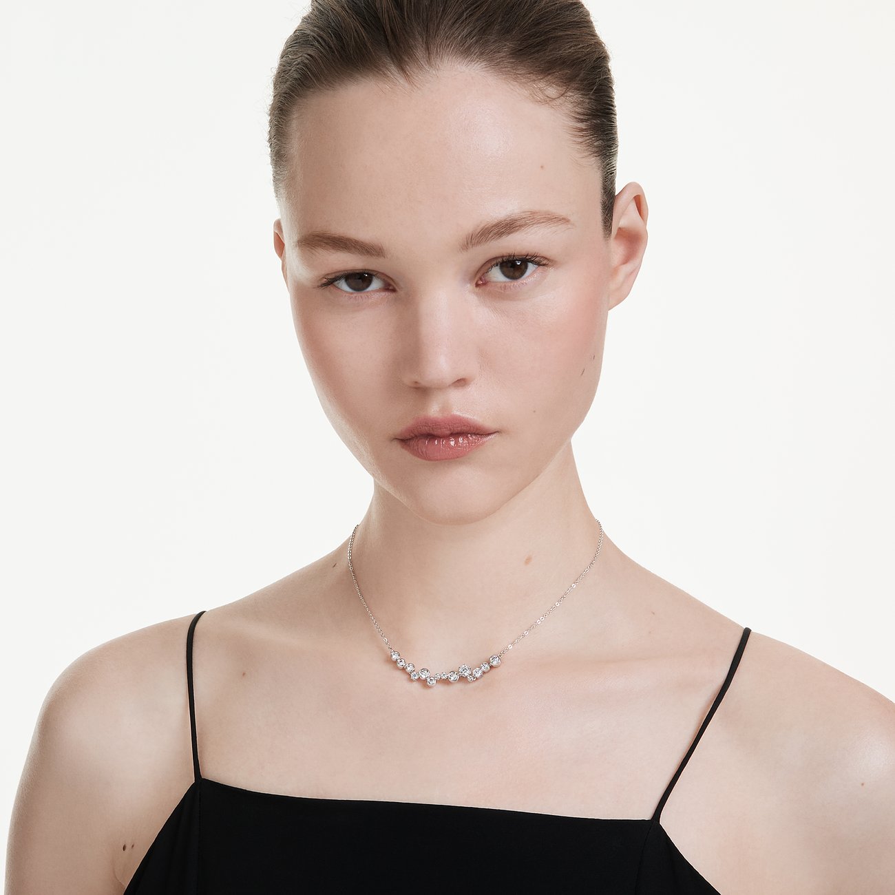 Ein Model trägt eine silberfarbene Swarovski Halskette aus Metall mit mehreren glänzenden Swarovski Kristallen.