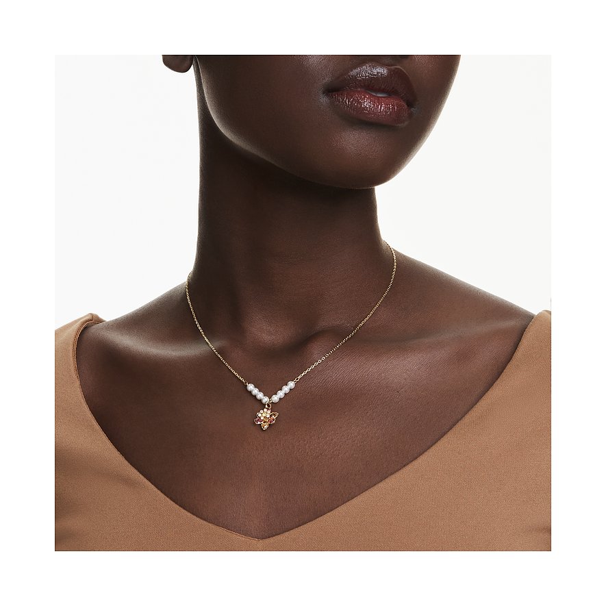 Nahaufnahme einer Frau mit goldfarbener Swarovski-Halskette, verziert mit Perlen und einem Farbkristall-Anhänger.