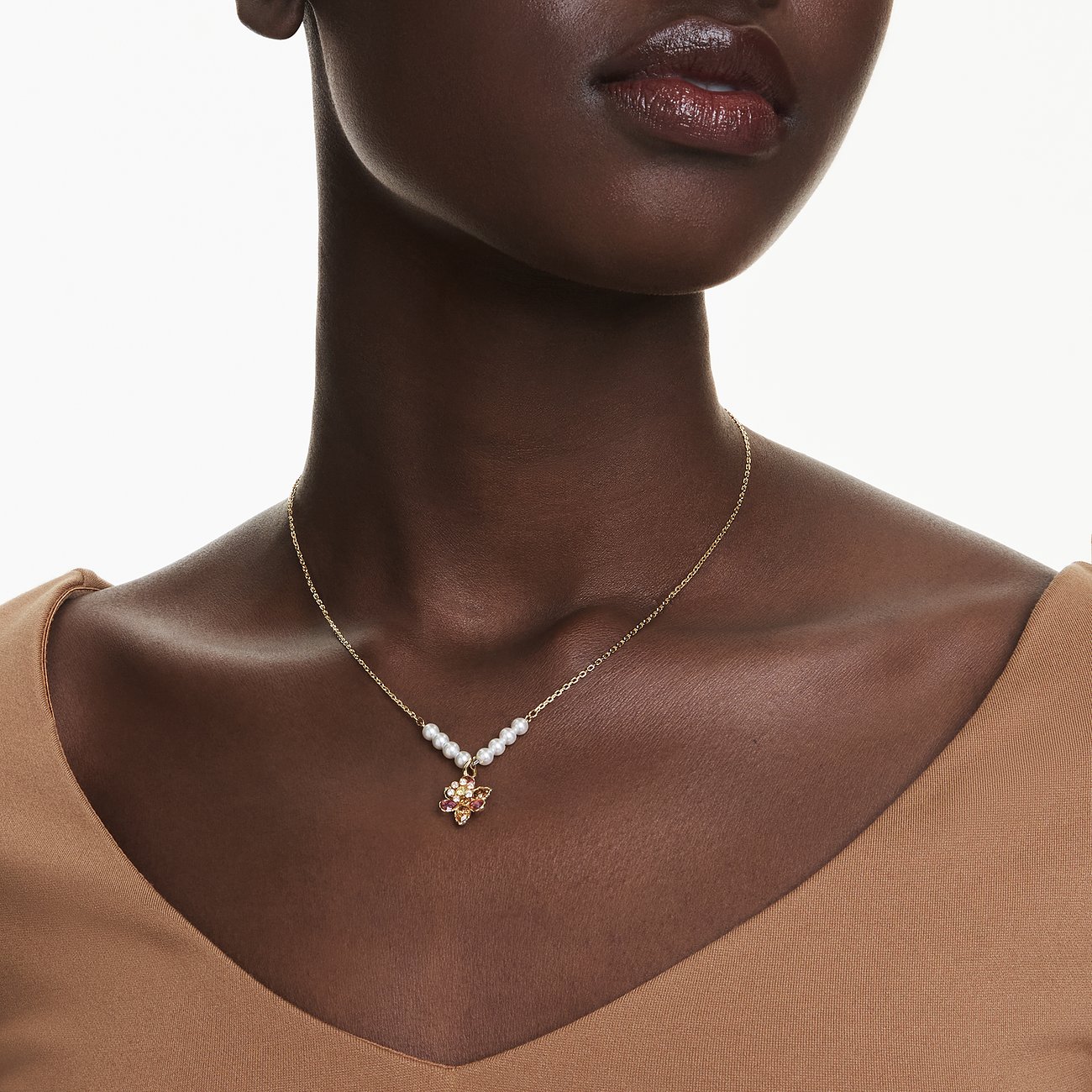 Nahaufnahme einer Frau mit goldfarbener Swarovski-Halskette, verziert mit Perlen und einem Farbkristall-Anhänger.