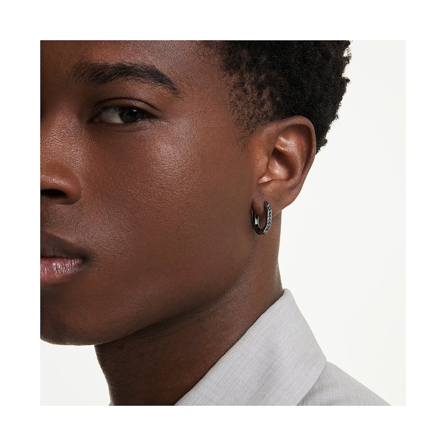 Nahaufnahme: Gesicht einer Person mit einem einzelnen schwarzen Swarovski Ohrring aus Metall mit funkelnden Farbedelsteinen.