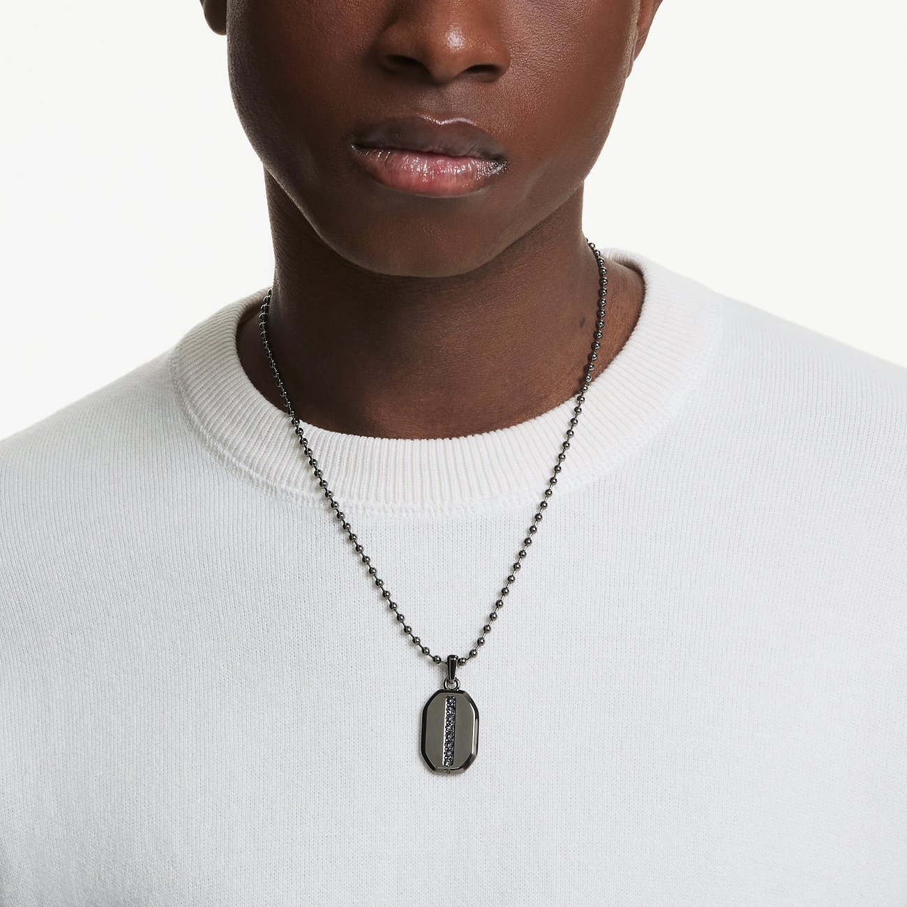 Nahaufnahme eines Modells, das eine Swarovski Halskette mit einem dunklen Anhänger aus Metall und Swarovski-Kristallen trägt.