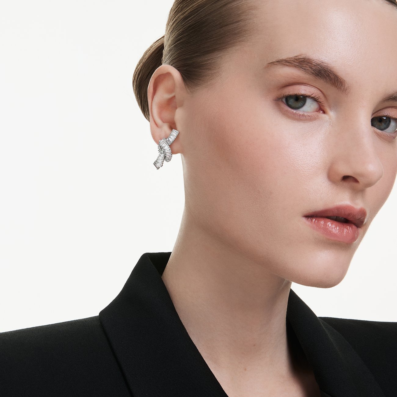 Close-up van model met glinsterende zilveren Swarovski oorsieraden van metaal met vele kleine kristallen.