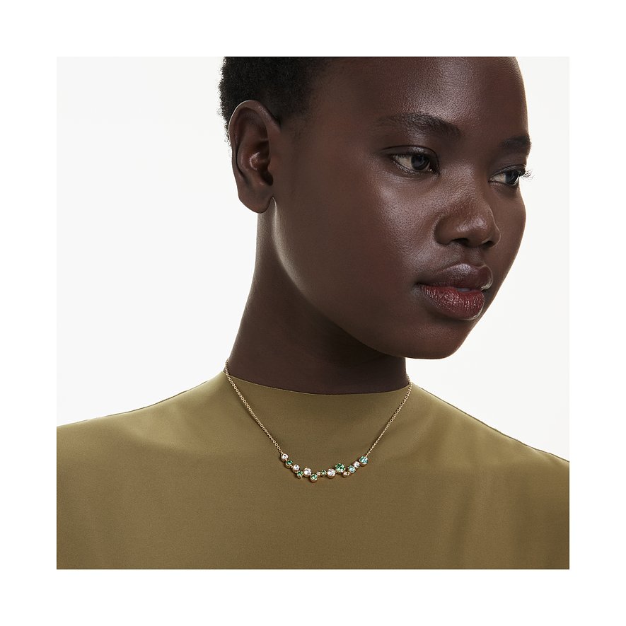 Eine Frau trägt eine Swarovski Halskette aus Metall mit bunten Swarovski-Kristallen in Grün und Weiß.