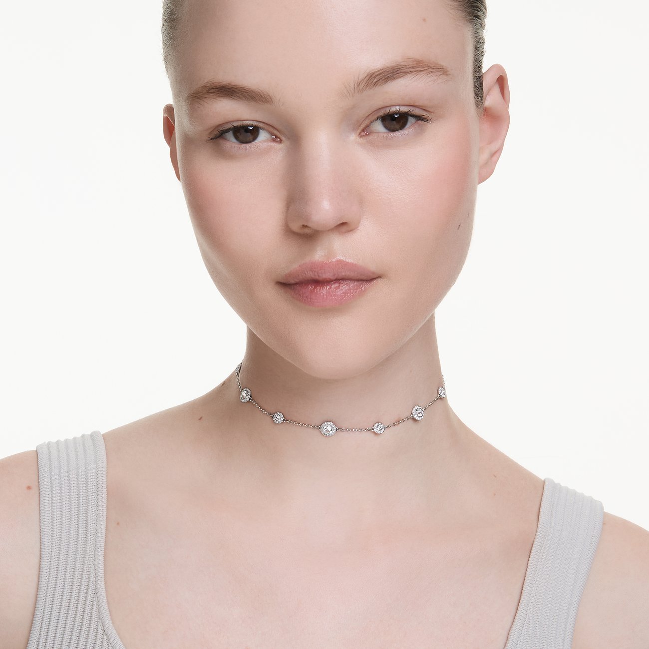 Model trägt ein Swarovski Halsband aus Metall mit funkelnden Swarovski Kristallen als Farbstein. Nahaufnahme.