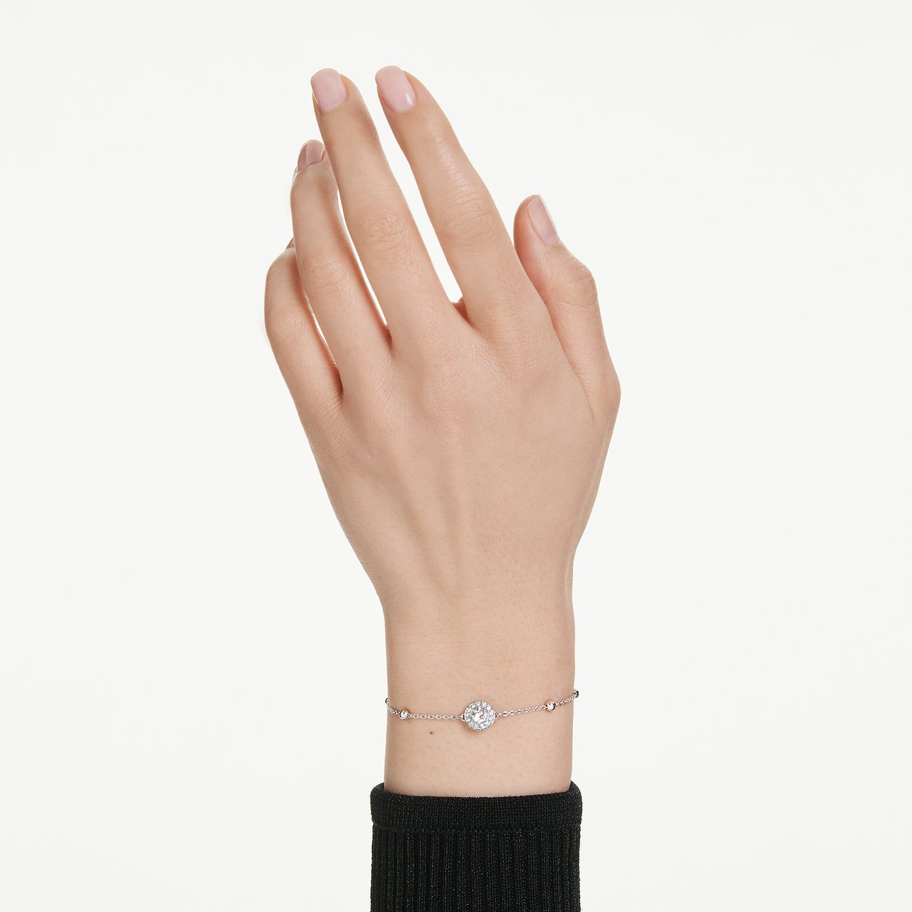 Eine Hand, die einen Swarovski Armschmuck aus Metall mit zentralem, runden, klaren Swarovski Kristall trägt.