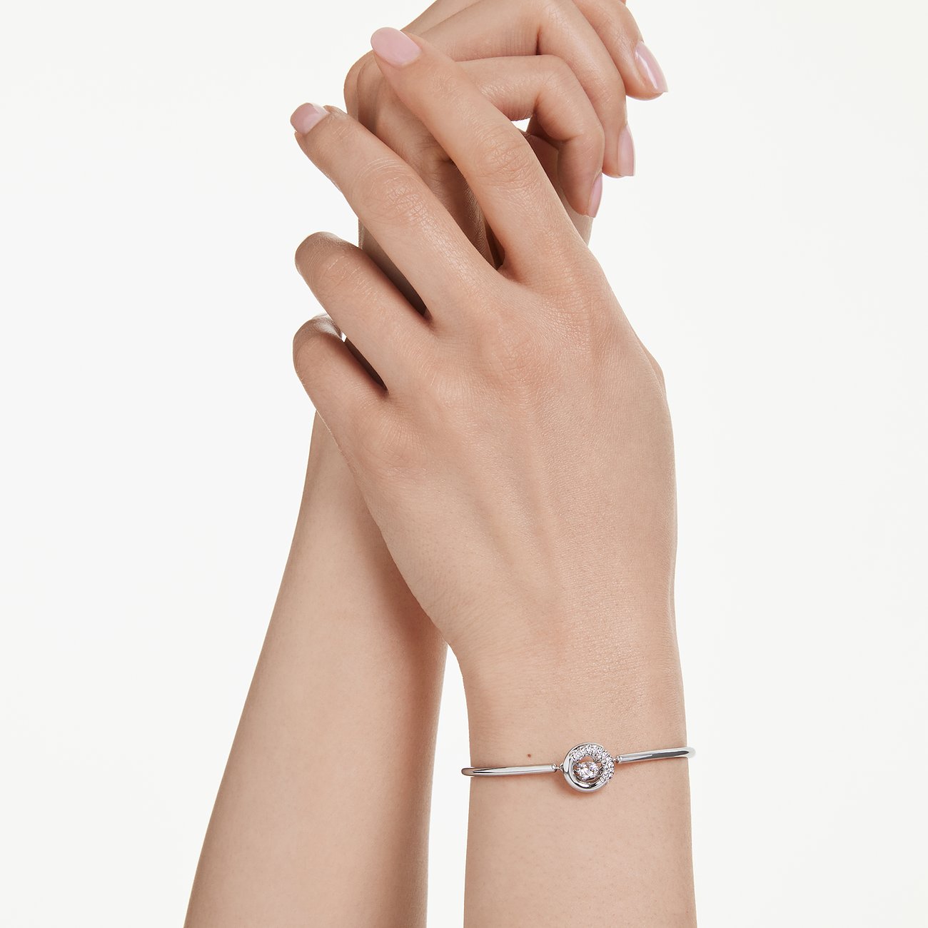 Am Handgelenk getragener Swarovski Armreif aus Metall mit einem rosafarbenen Swarovski-Kristall in der Mitte.