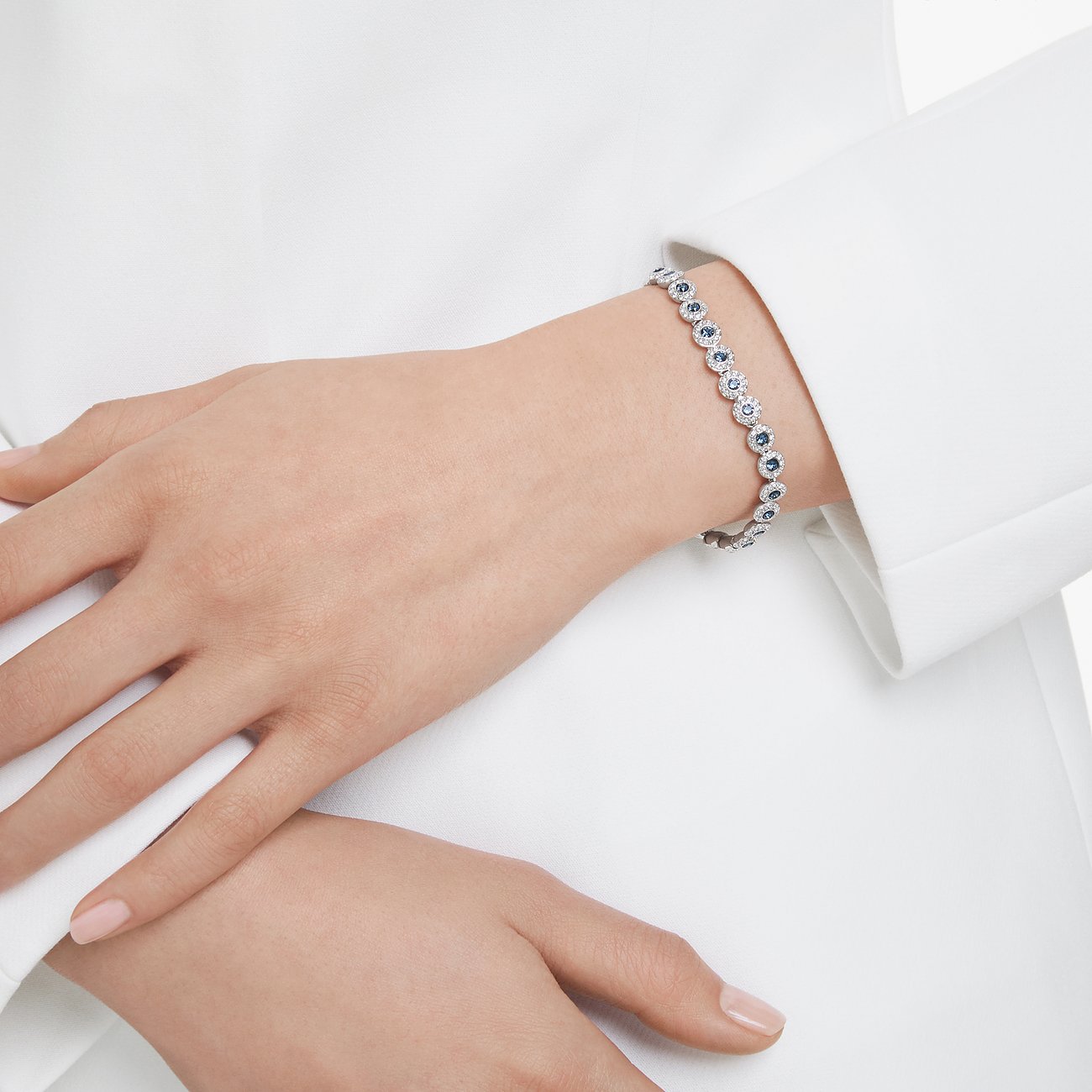 Metalen Swarovski armband, aan de pols gedragen, met blauwe en witte Swarovski kristallen. De armband glinstert.