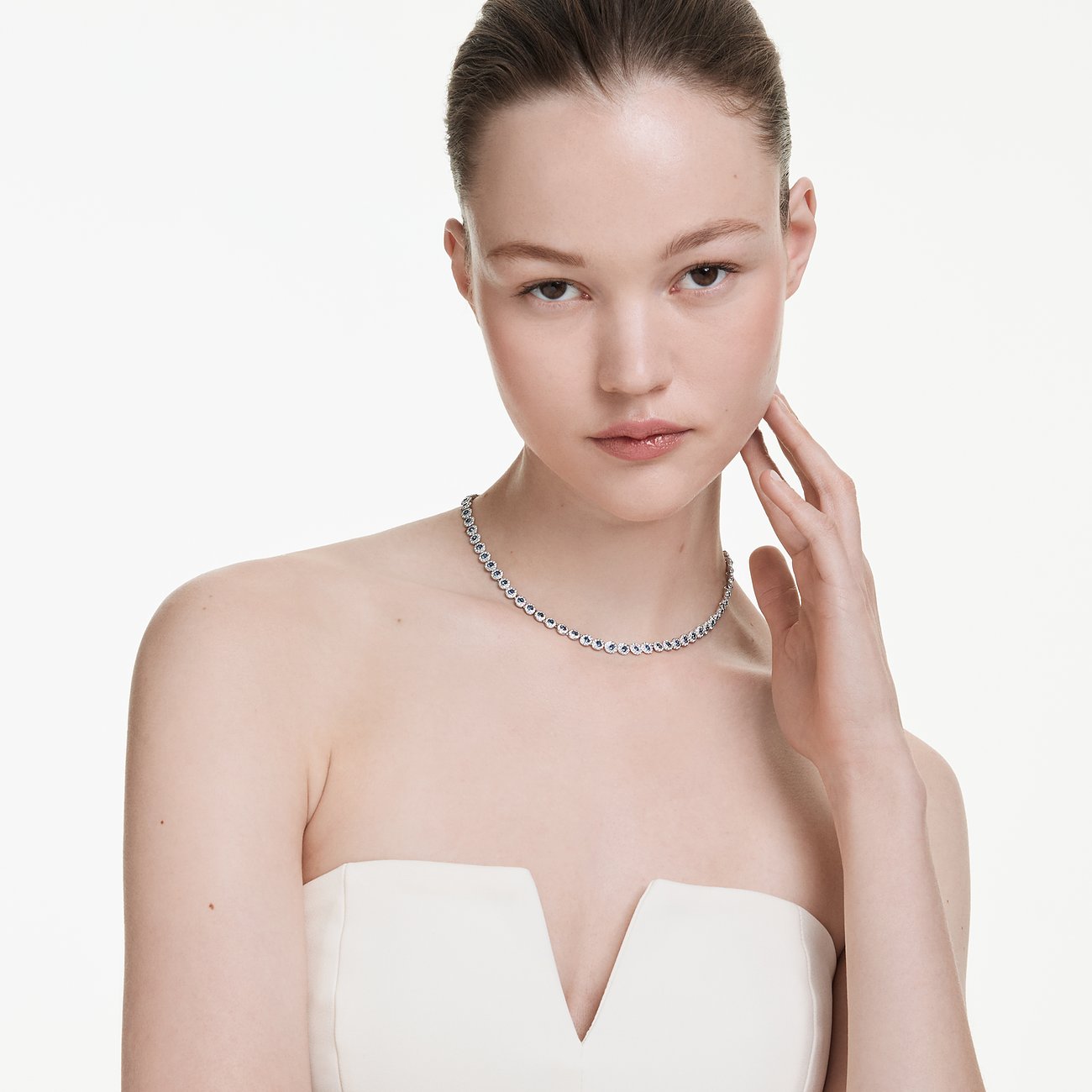 Model draagt een Swarovski metalen halsketting met kleurrijke edelstenen. De fijne ketting omhelst subtiel de nek.