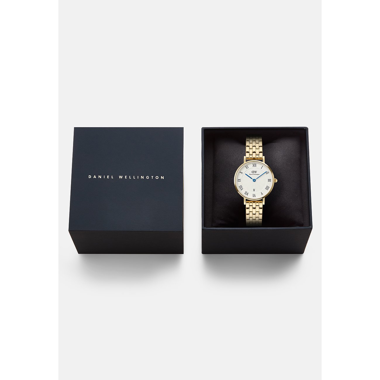 Eine goldfarbene Daniel Wellington Damenuhr aus Edelstahl liegt in einer schwarzen Box neben der Uhrenverpackung.