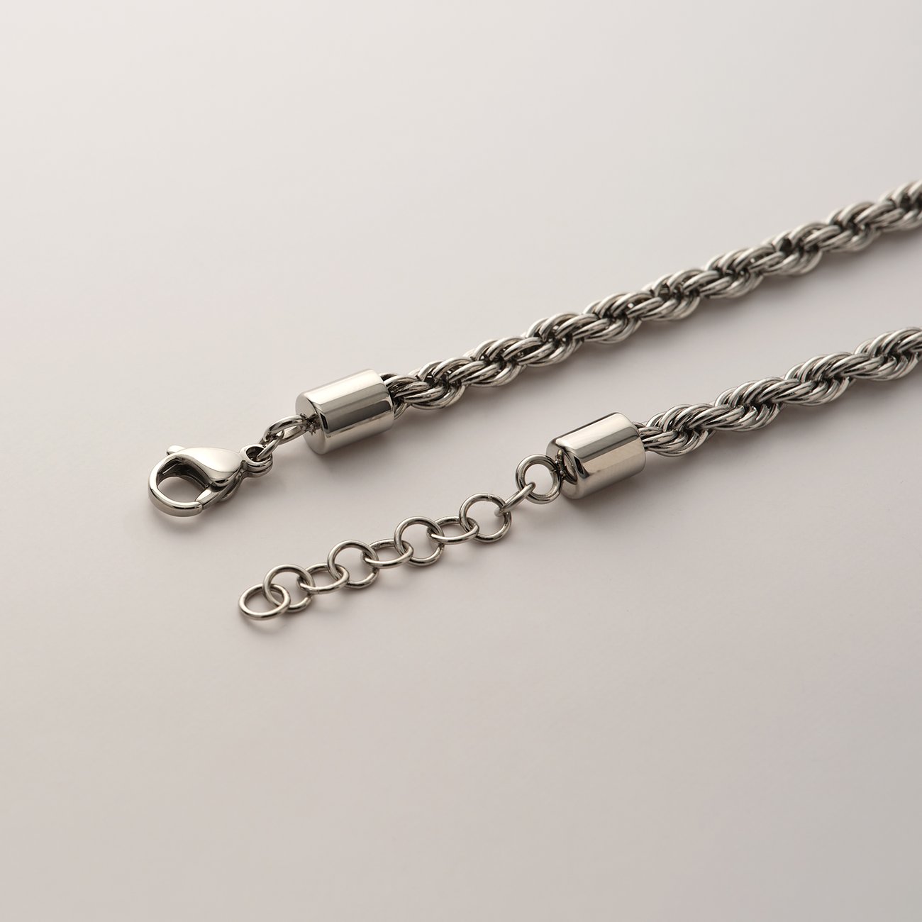 Ein FAVS Armschmuck aus gedrehtem Edelstahl mit Karabinerverschluss und Verlängerungskettchen.