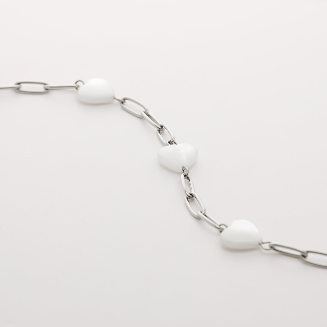Bracelet Guido Maria Kretschmer en acier inoxydable avec chaîne et cœurs en nacre blanche.