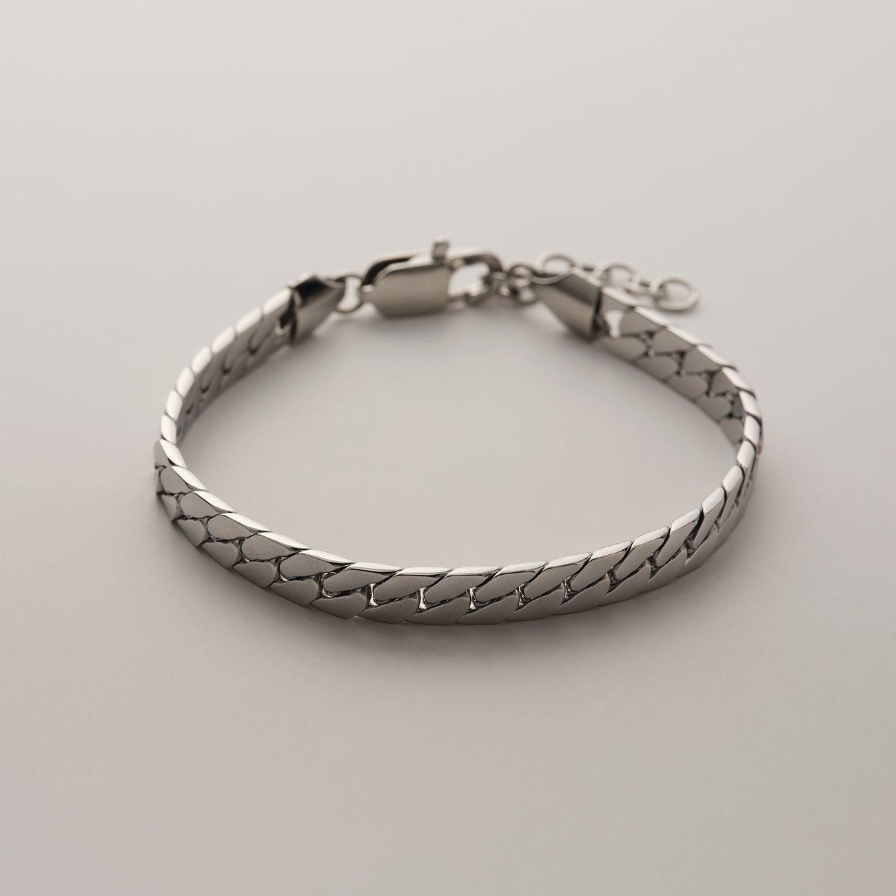 FAVS Armschmuck aus Edelstahl, ein flaches FAVS Armband mit ineinandergreifenden Gliedern, Verschluss liegt offen.