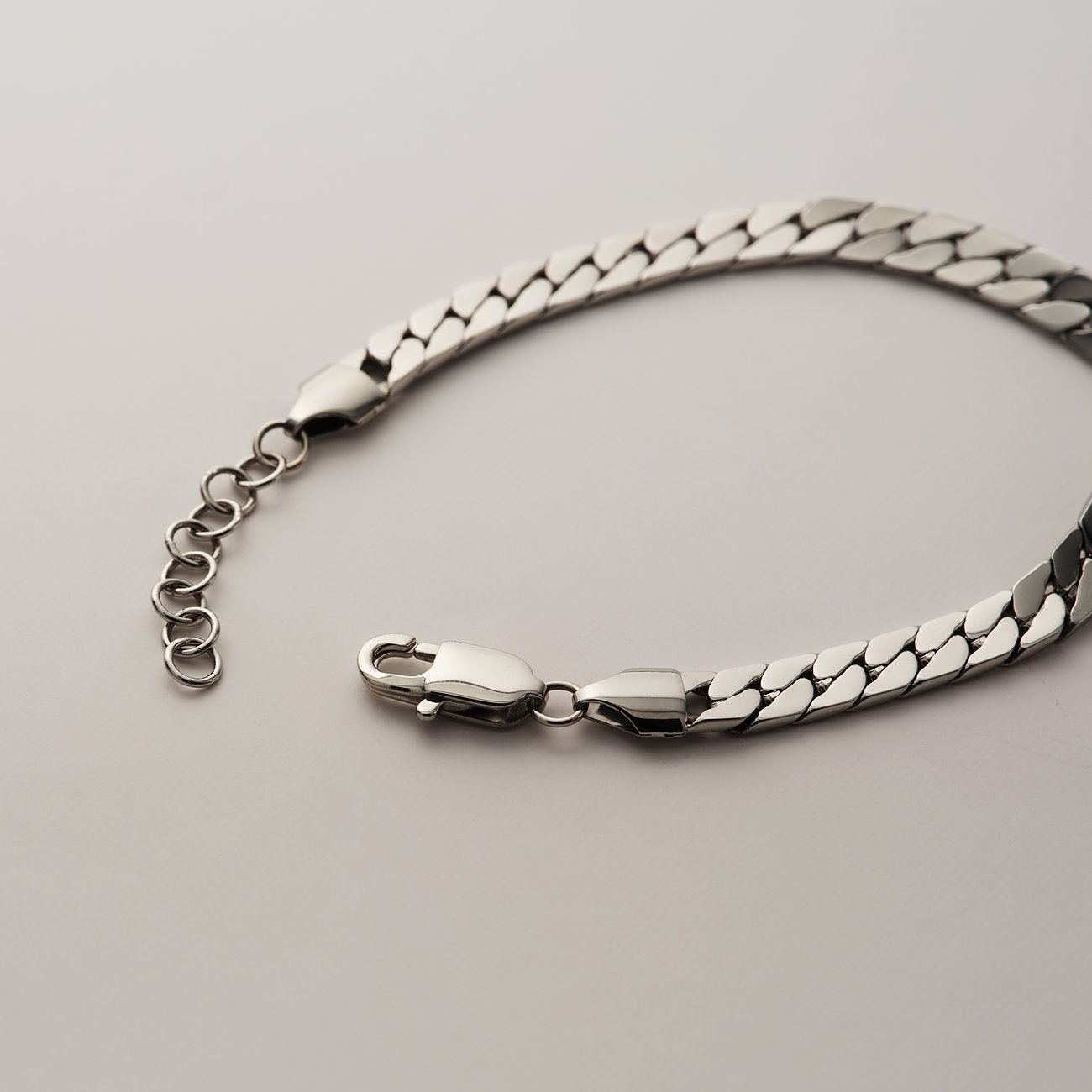 FAVS Edelstahl Armschmuck in Silber, leicht gebogen und von oben links nach unten rechts im Bild. Karabinerhaken.