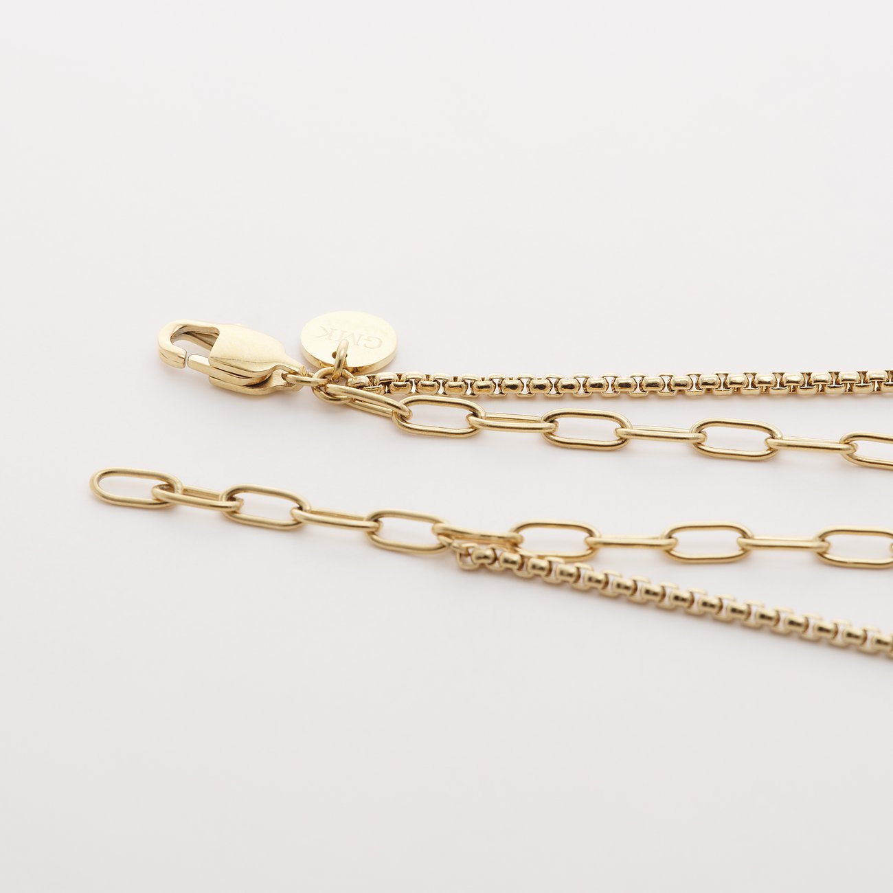 Detailaufnahme einer Guido Maria Kretschmer Armbandverlängerung aus goldfarbenem Edelstahl mit Karabinerverschluss.