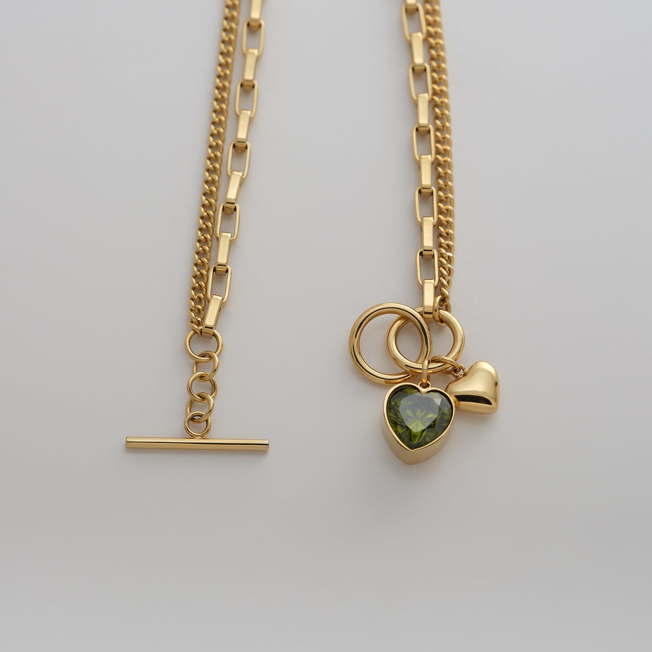 Guido Maria Kretschmer Armband, goldfarbener Edelstahl, zwei Ketten, Herz-Anhänger mit grünem Zirkonia-Farbstein.