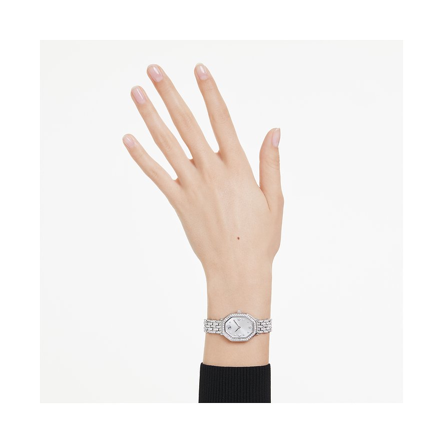 Een hand draagt een Swarovski unisex metalen horloge met sprankelende Swarovski-kristallen en een achthoek wijzerplaat.