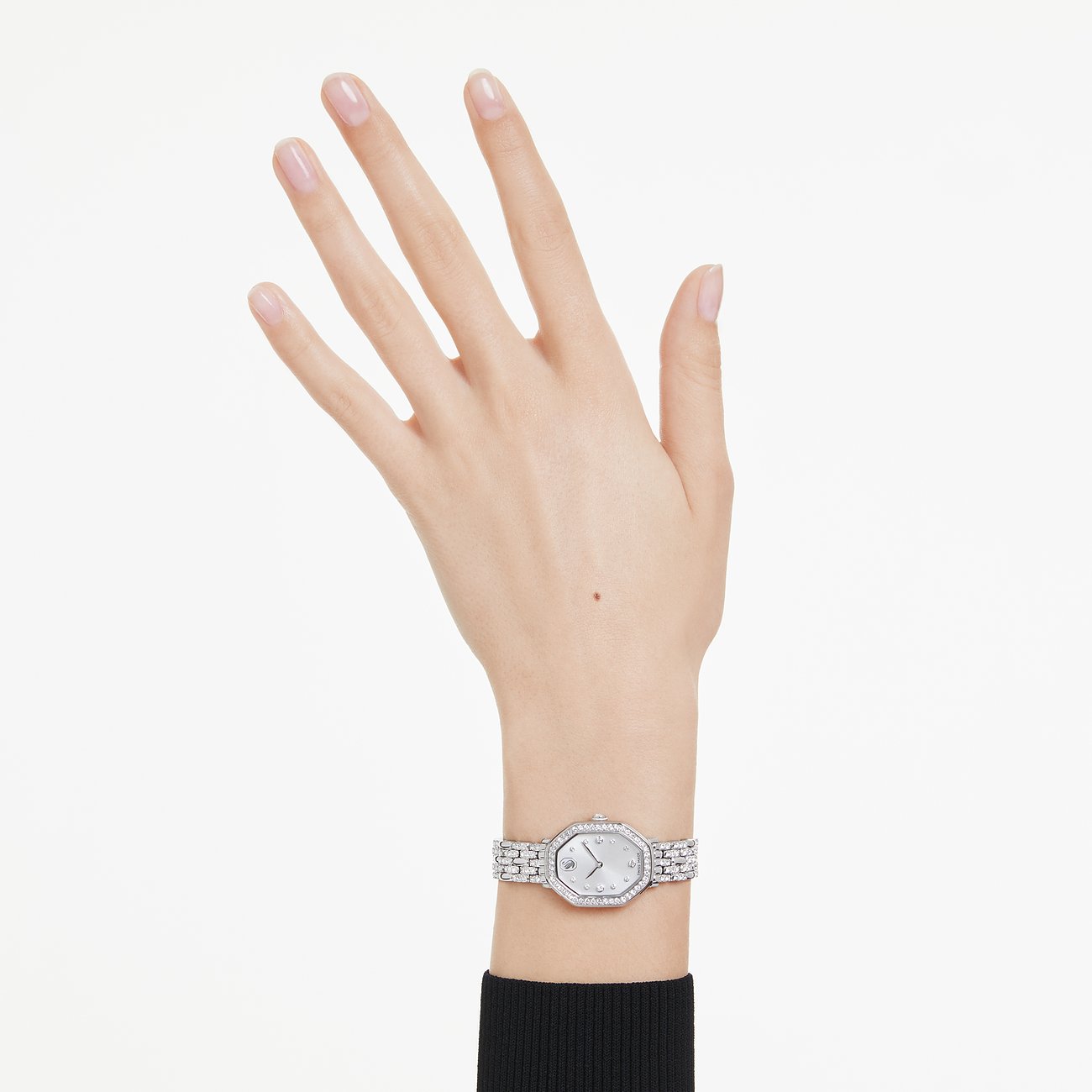 Een hand draagt een Swarovski unisex metalen horloge met sprankelende Swarovski-kristallen en een achthoek wijzerplaat.