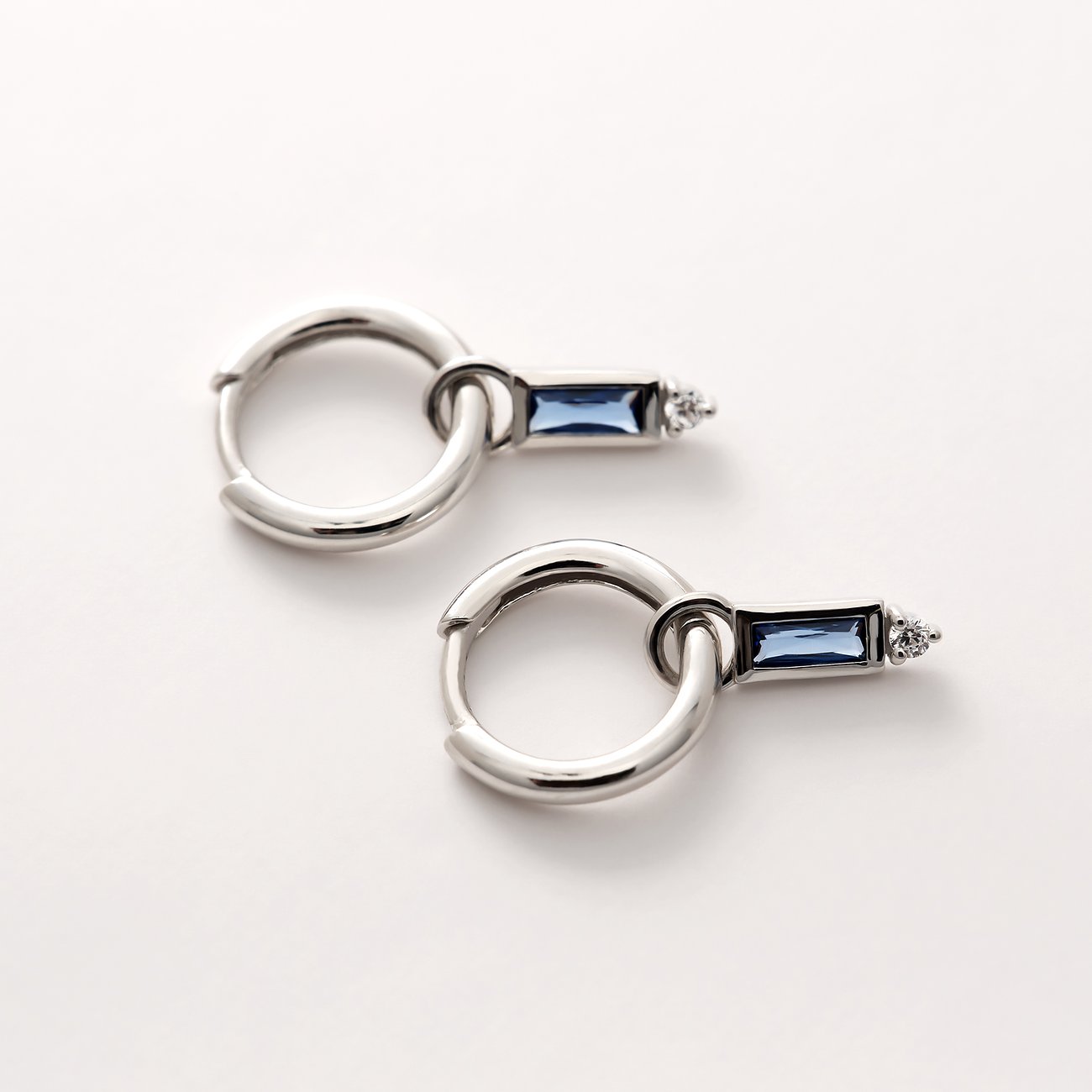 Un paio di orecchini Guido Maria Kretschmer in argento riciclato 925 con pietre di zircone colorate, oblique.