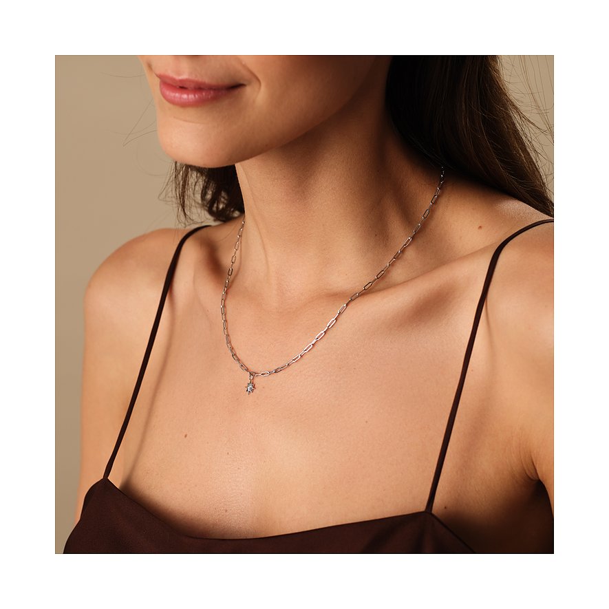 Een vrouw draagt een Guido Maria Kretschmer ketting van gerecycled 925 zilver met een fijne ketting en sterhanger.