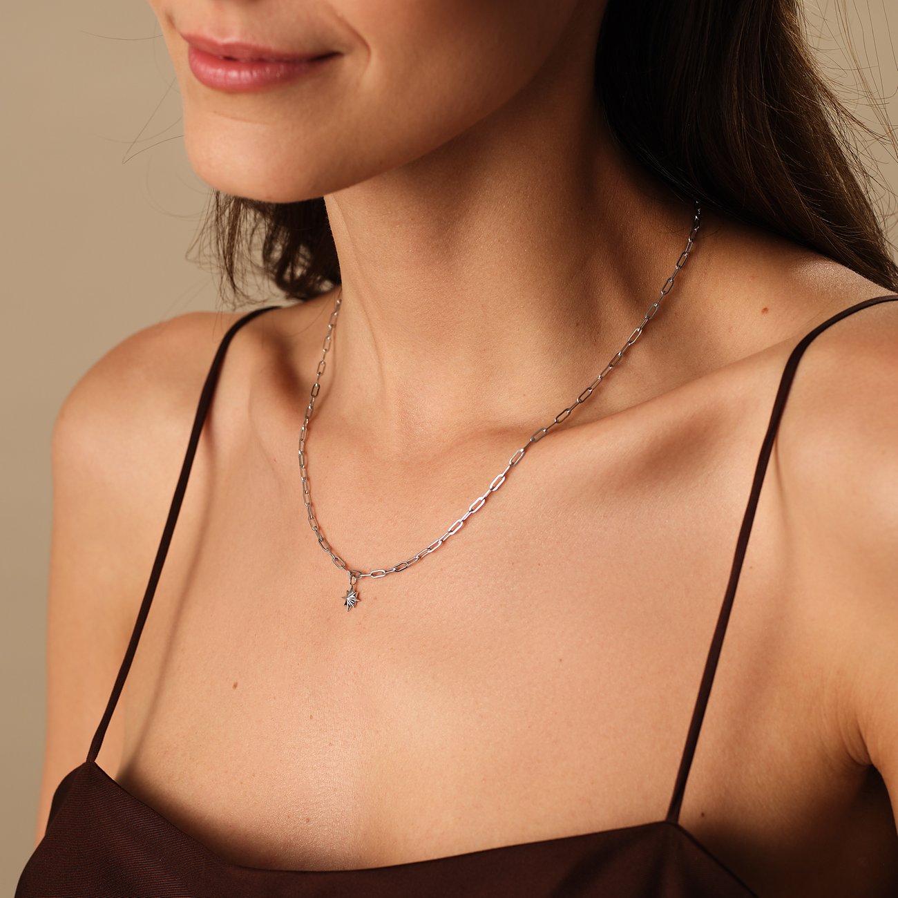 Een vrouw draagt een Guido Maria Kretschmer ketting van gerecycled 925 zilver met een fijne ketting en sterhanger.