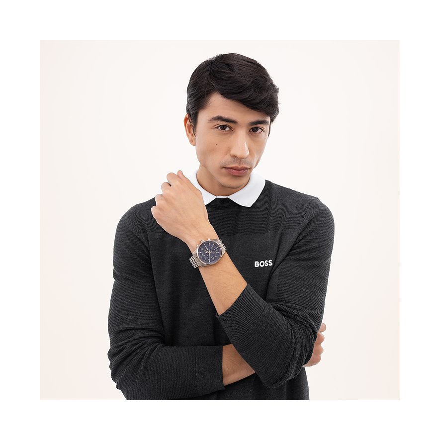Ein Mann im grauen Pullover hält seinen Arm angewinkelt und zeigt die Boss Herrenuhr aus Edelstahl am Handgelenk.