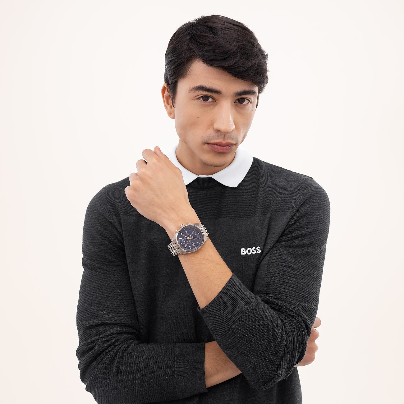 Ein Mann im grauen Pullover hält seinen Arm angewinkelt und zeigt die Boss Herrenuhr aus Edelstahl am Handgelenk.