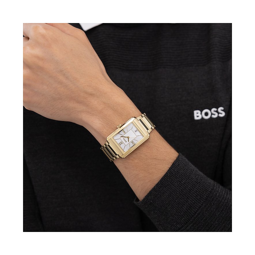 Am Handgelenk eines Mannes wird eine goldfarbene Boss Herrenuhr aus Edelstahl mit rechteckigem Zifferblatt gezeigt.
