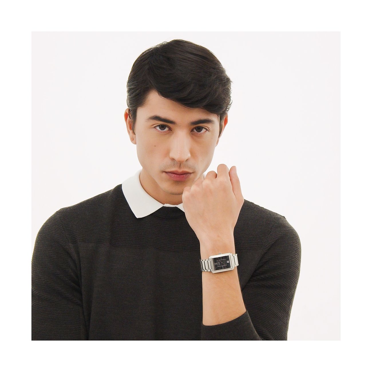Ein junger Mann mit dunklen Haaren trägt eine Boss Herrenuhr aus silberfarbenem Edelstahl mit schwarzem Zifferblatt.