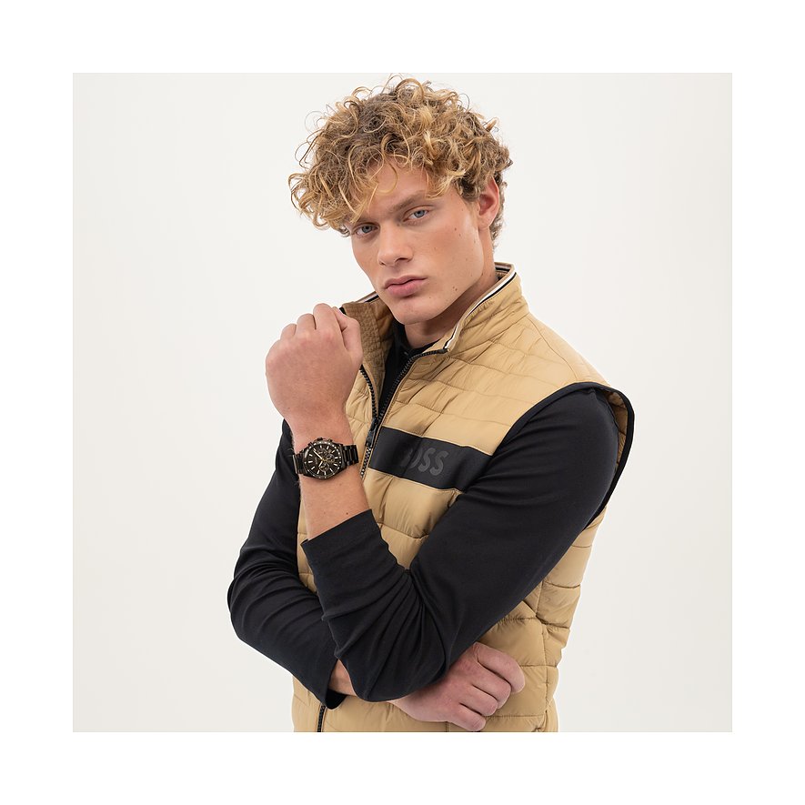 Ein blondgelockter Mann trägt eine schwarze Herrenuhr aus Edelstahl von Boss an seinem linken Handgelenk.