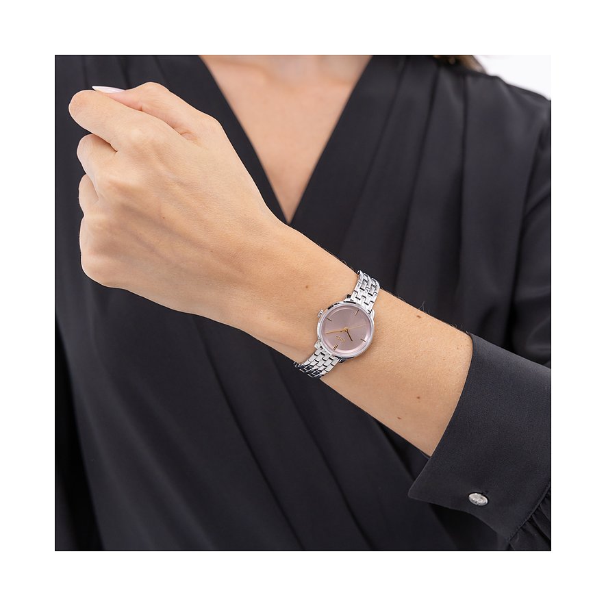 Am Handgelenk einer Frau ist eine Boss Damenuhr aus Edelstahl mit einem roséfarbenen Zifferblatt zu sehen.