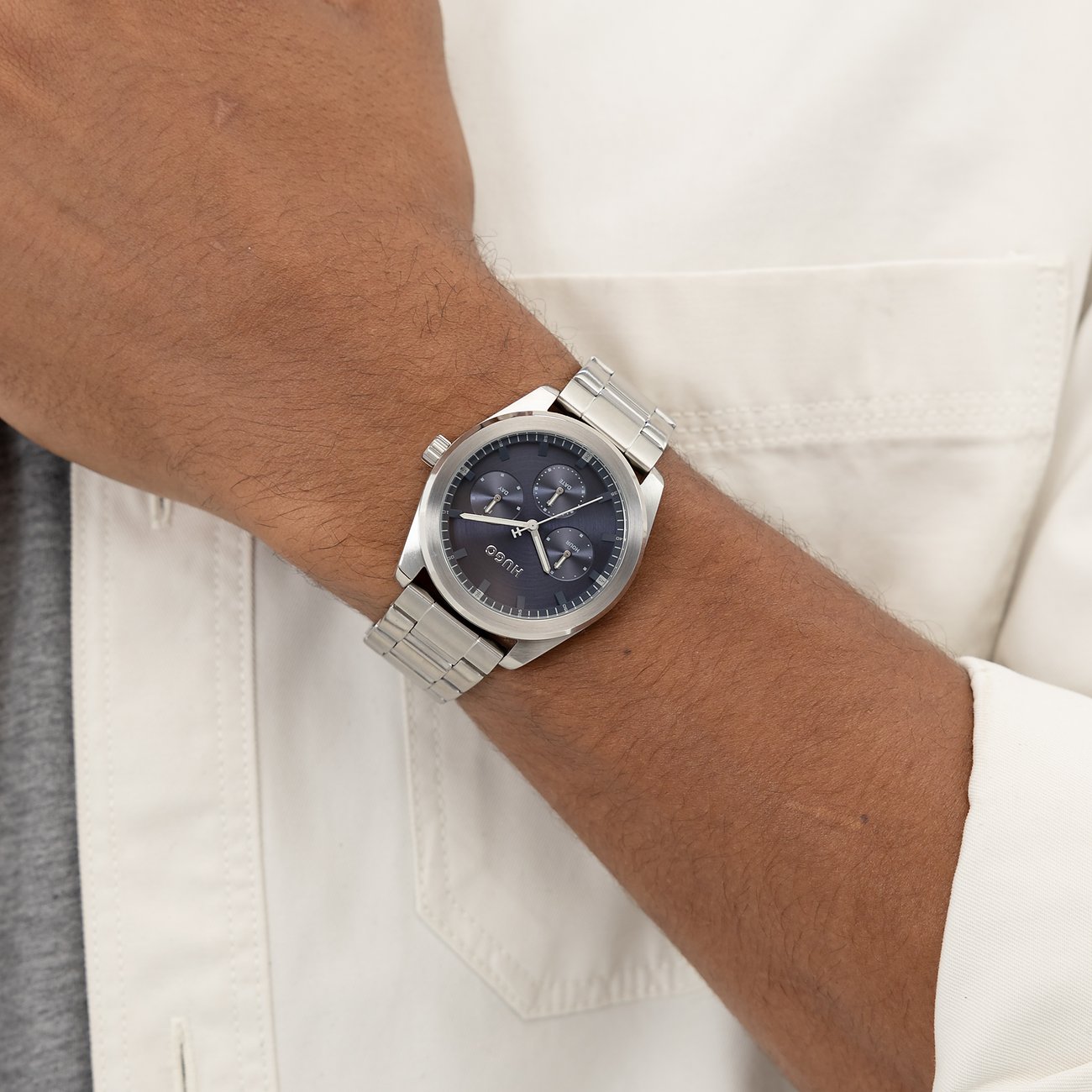 Am Handgelenk eines Mannes getragene Hugo Herrenuhr aus Edelstahl mit Chronographenfunktion und dunkelblauem Zifferblatt.