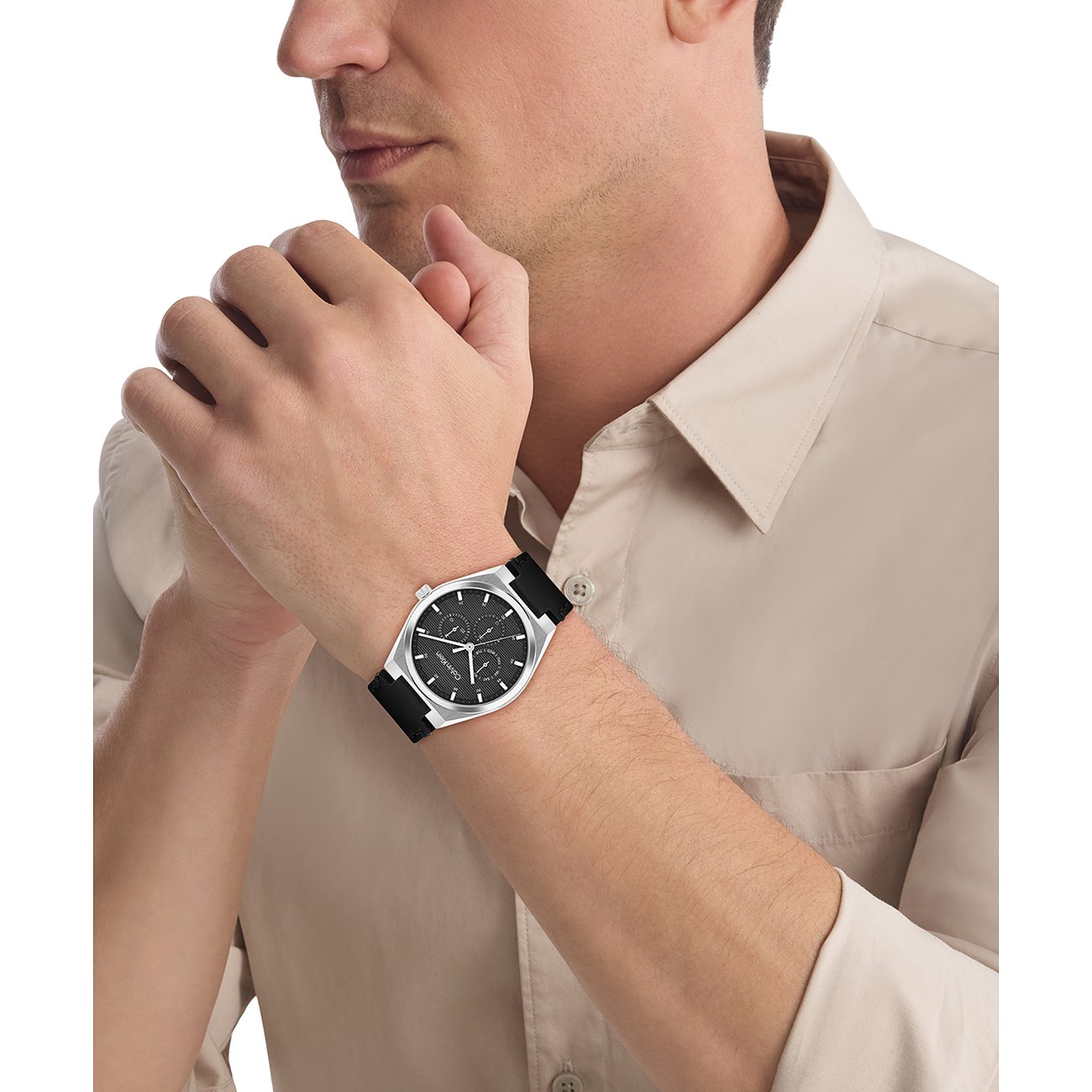 Een man draagt een Calvin Klein herenhorloge van roestvrij staal met zwarte wijzerplaat en zwarte band om zijn pols.