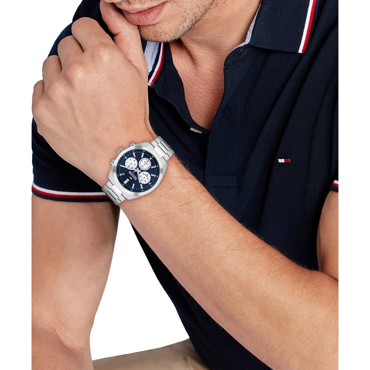 Ein Mann trägt eine Tommy Hilfiger Herrenuhr aus Edelstahl mit blauem Ziffernblatt an seinem linken Handgelenk.