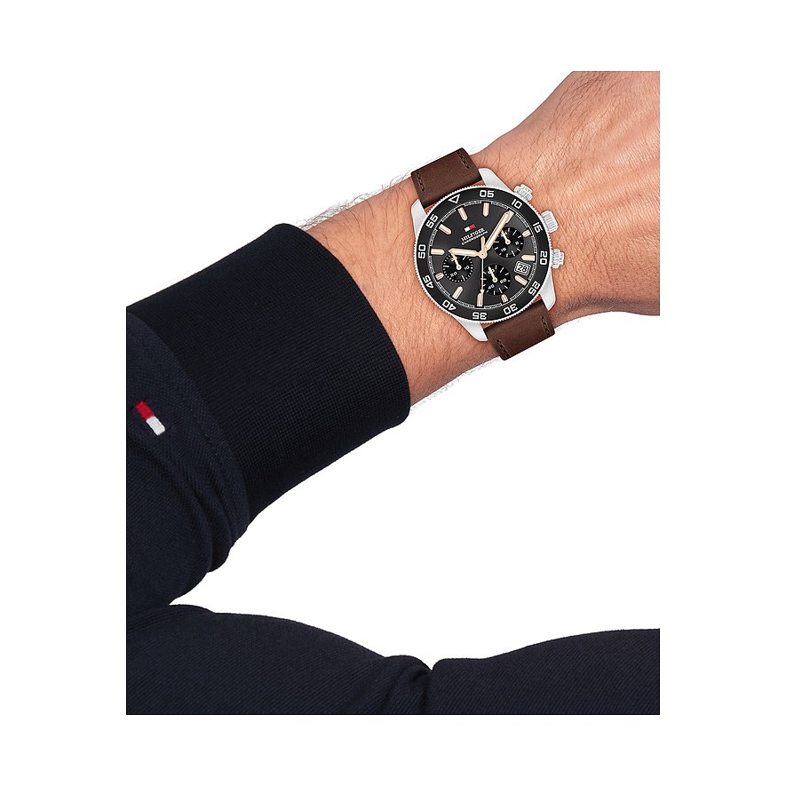 Am Handgelenk getragene Tommy Hilfiger Herrenuhr aus Edelstahl und Aluminium mit braunem Lederarmband.