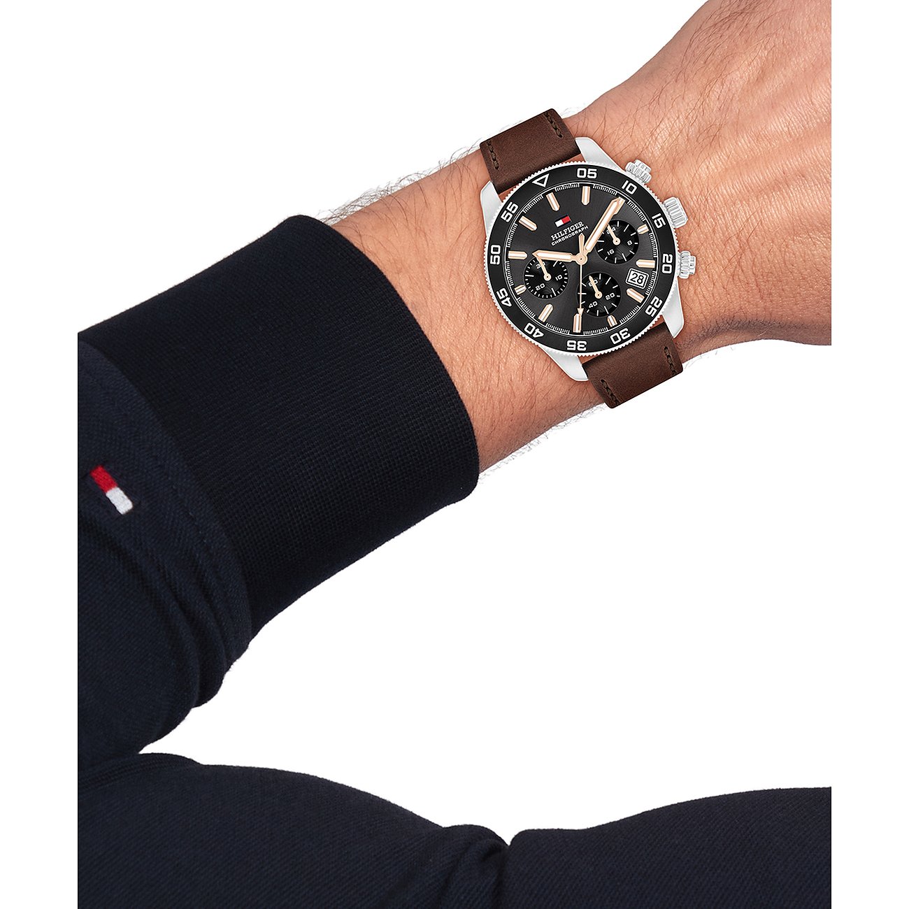 Am Handgelenk getragene Tommy Hilfiger Herrenuhr aus Edelstahl und Aluminium mit braunem Lederarmband.