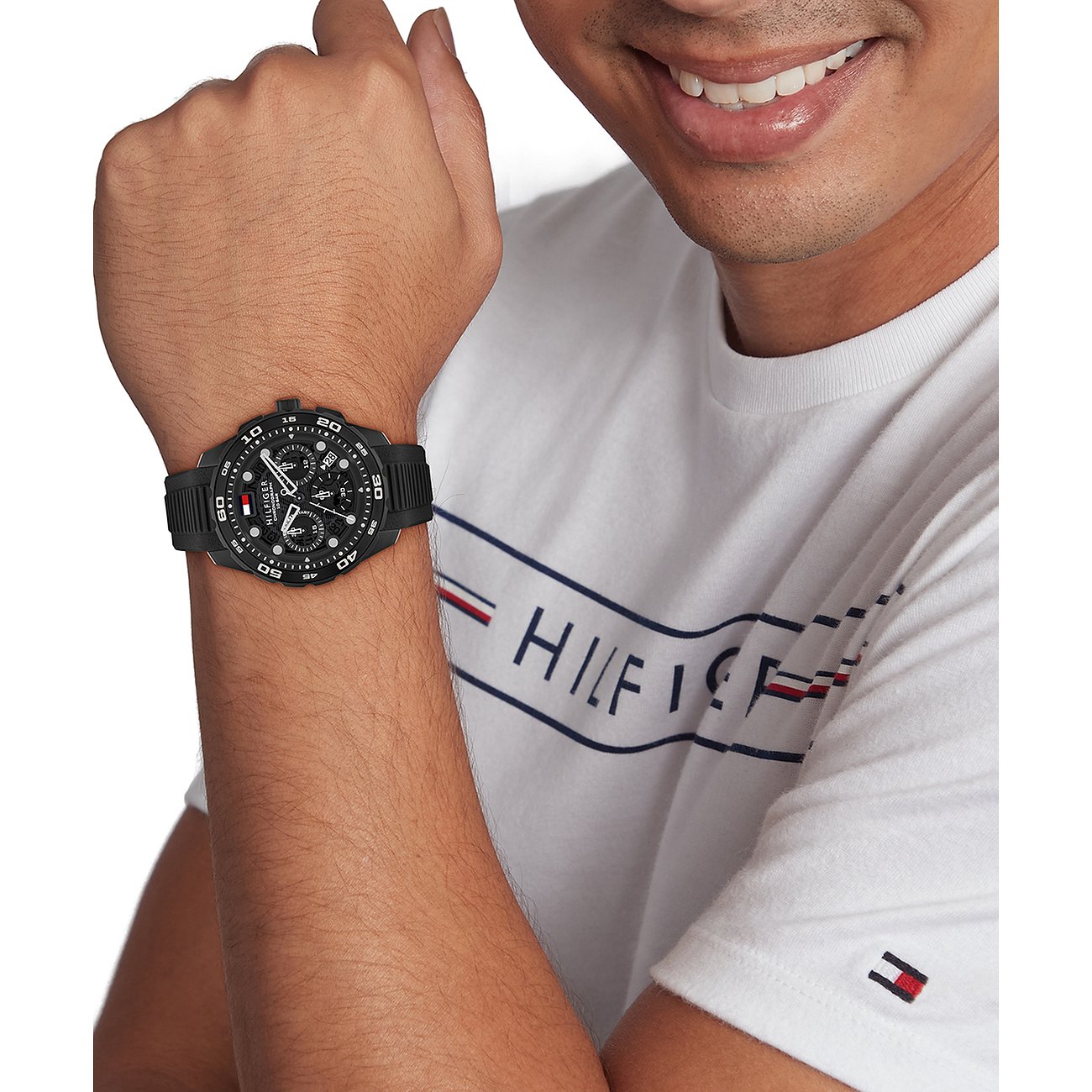 Nahaufnahme einer schwarzen Tommy Hilfiger Herrenuhr aus Edelstahl und Aluminium am Handgelenk eines Mannes.