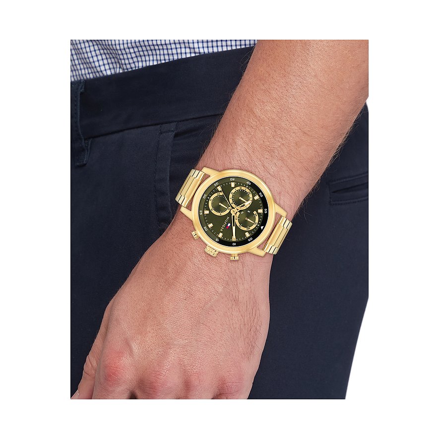 Goudkleurig roestvrijstalen Tommy Hilfiger herenhorloge met donkere wijzerplaat, gedragen om de pols.