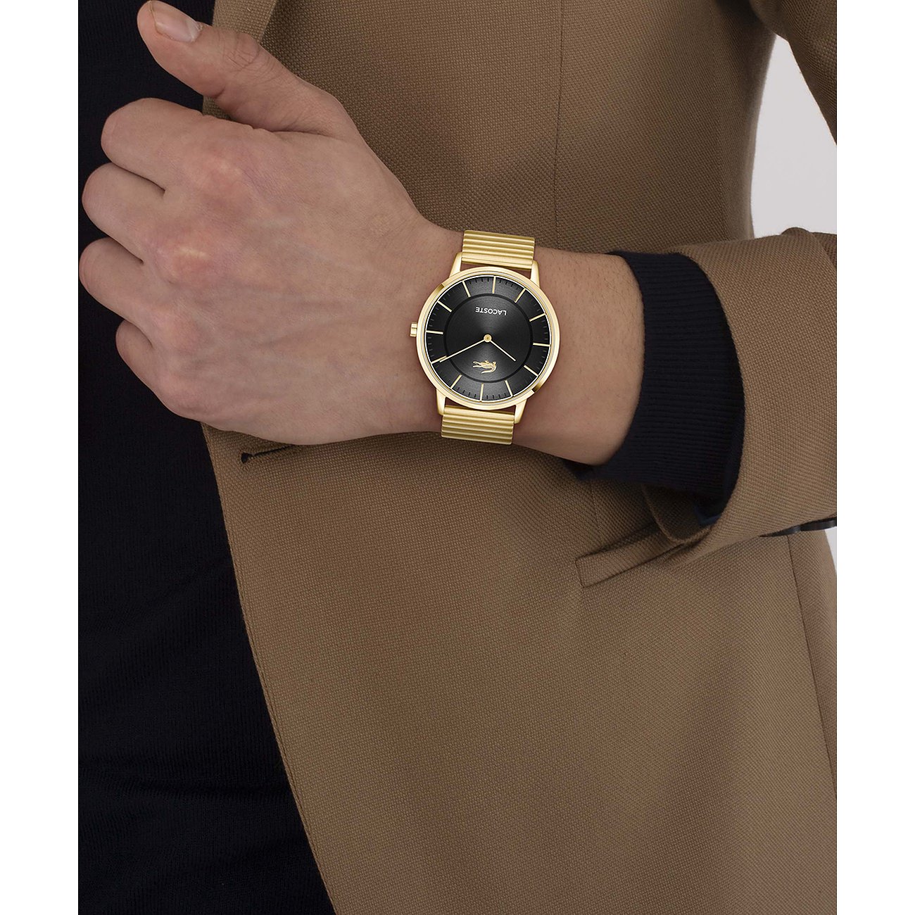 Am Handgelenk eines Mannes getragene goldene Lacoste Herrenuhr aus Edelstahl mit schwarzem Zifferblatt.