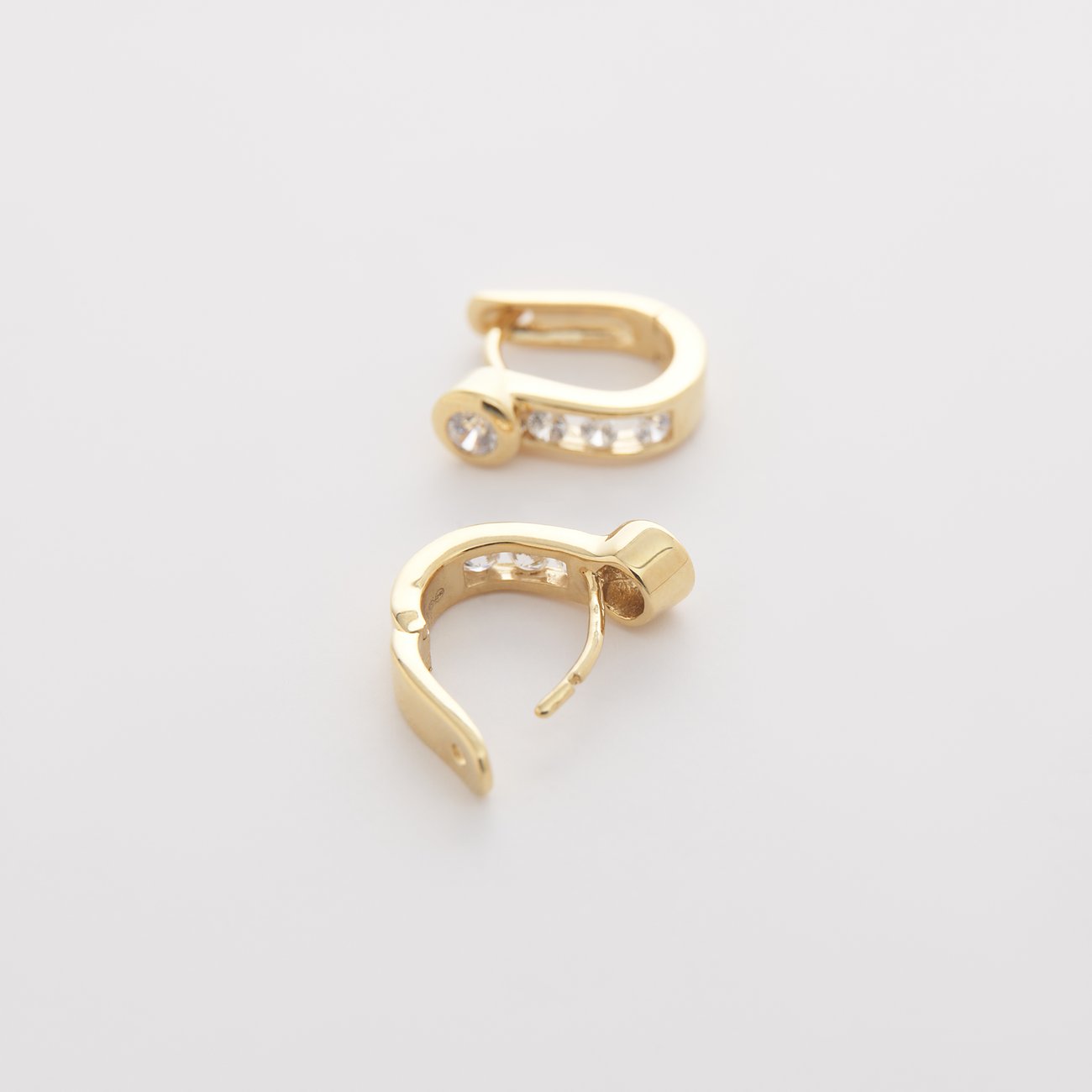 Ein Paar goldfarbene CHRIST Ohrringe aus 585 Weißgold, besetzt mit funkelnden Diamanten, von oben fotografiert.