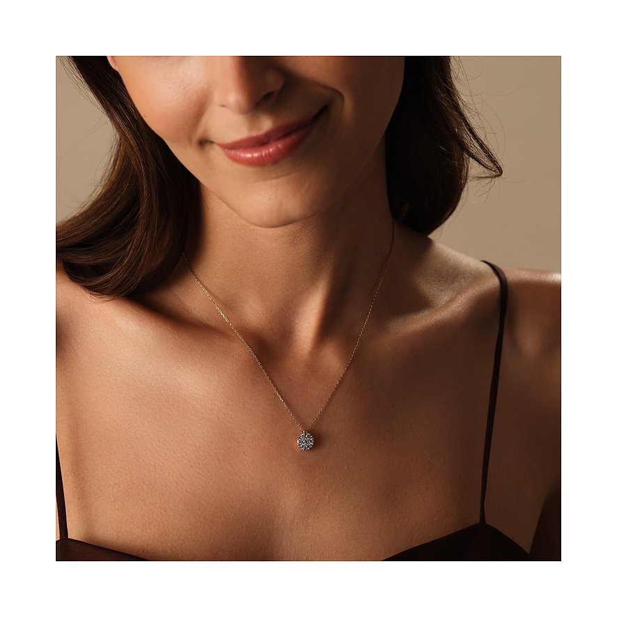 Nahaufnahme einer lächelnden Frau, die eine CHRIST Halskette aus 585er Gelbgold mit funkelndem Diamant-Anhänger trägt.