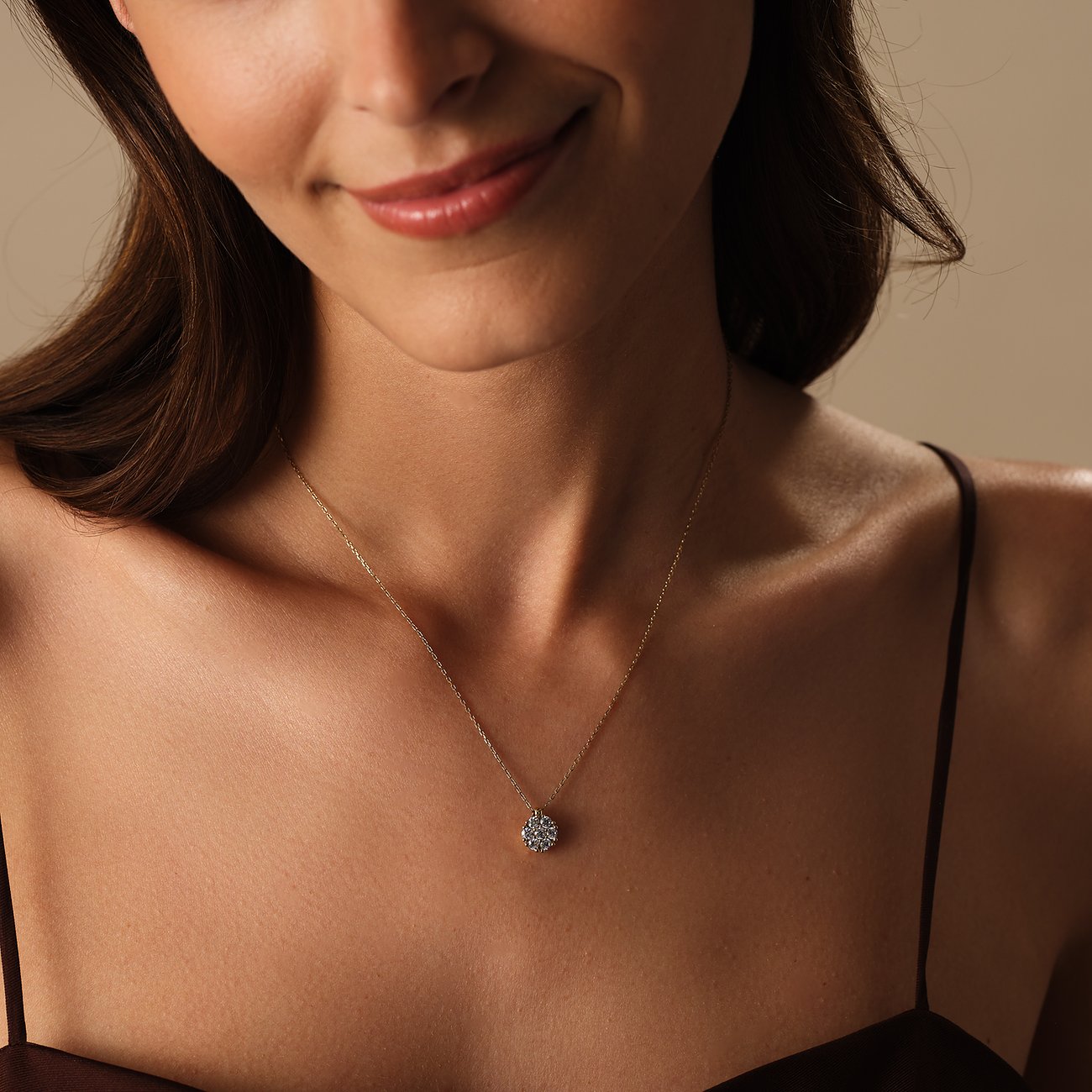 Nahaufnahme einer lächelnden Frau, die eine CHRIST Halskette aus 585er Gelbgold mit funkelndem Diamant-Anhänger trägt.