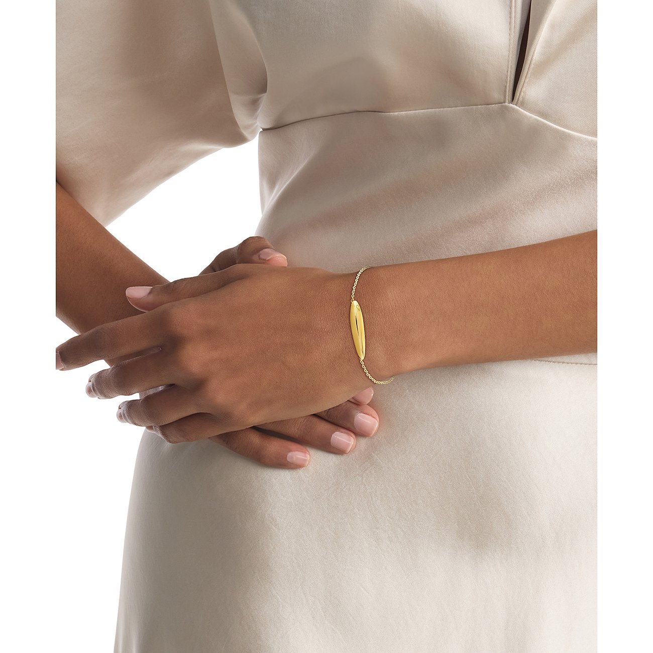 Ein Calvin Klein Armschmuck aus gelbgoldfarbenem Edelstahl sitzt am Handgelenk eines Models.